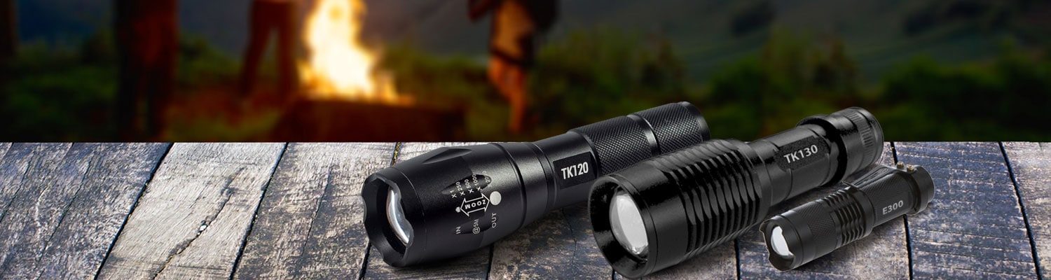 a variety of LED flashlights on a wood table in a camp ground