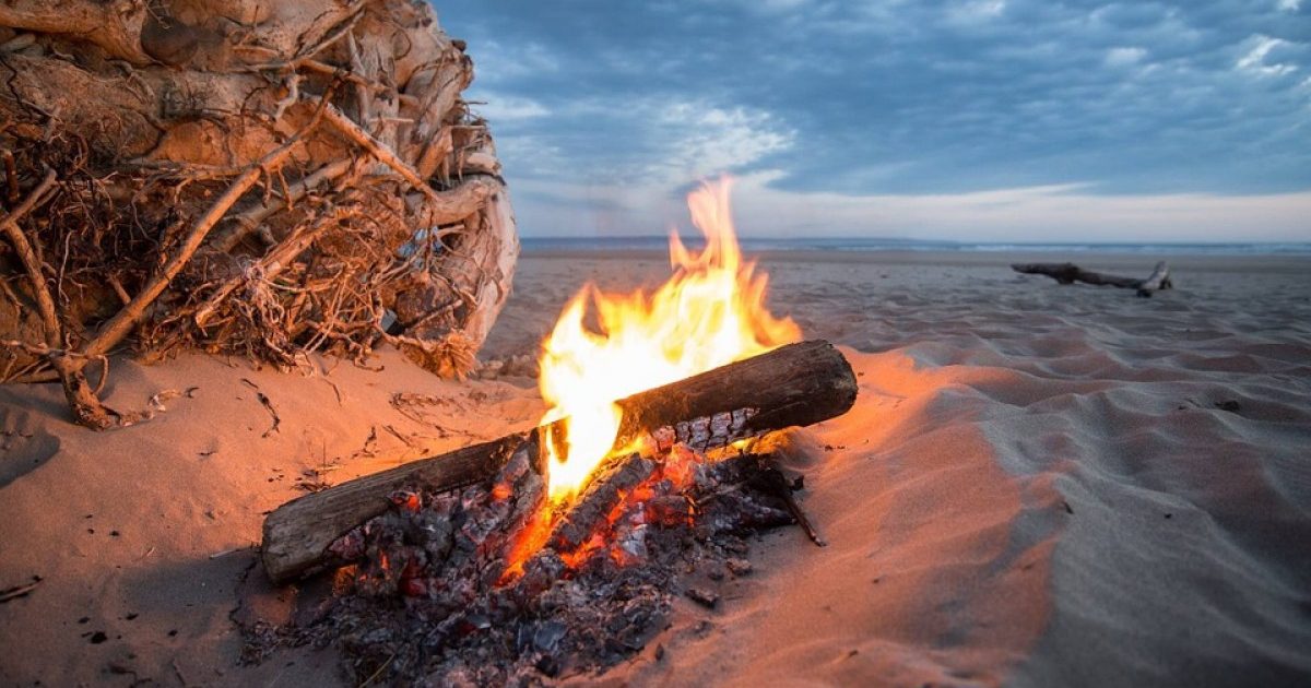 Beach Camping Site with Campfire on Sand During the Sunset