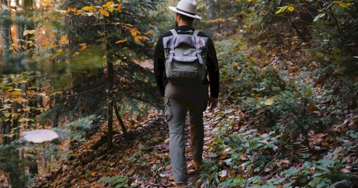 a backpacker on a hiking trail with a hat and backpack