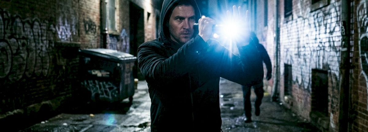 bright strobe flashlight shining in a dark alley, illuminating a person holding it for self‑defense