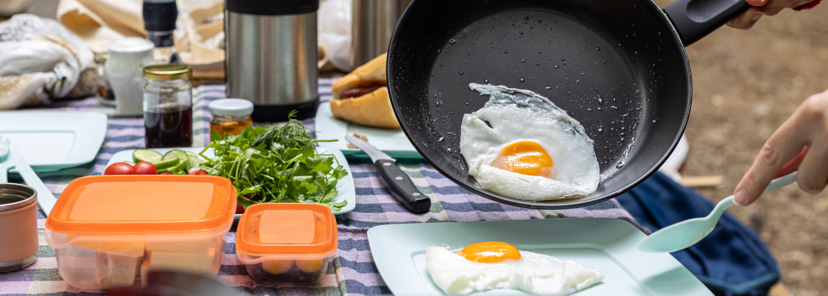 a table with camping cookware, stove, food and utensils