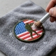 Close‑up of a colorful embroidered morale patch being gently hand‑washed on a microfiber cloth
