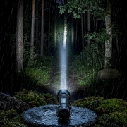 showing light beam distance at night in a forest