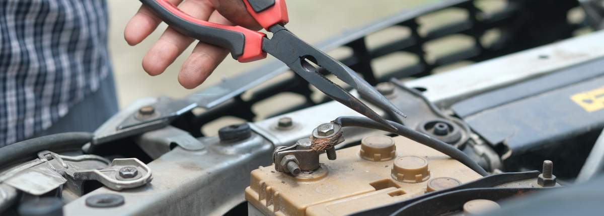 man using tool to disconnect a car battery