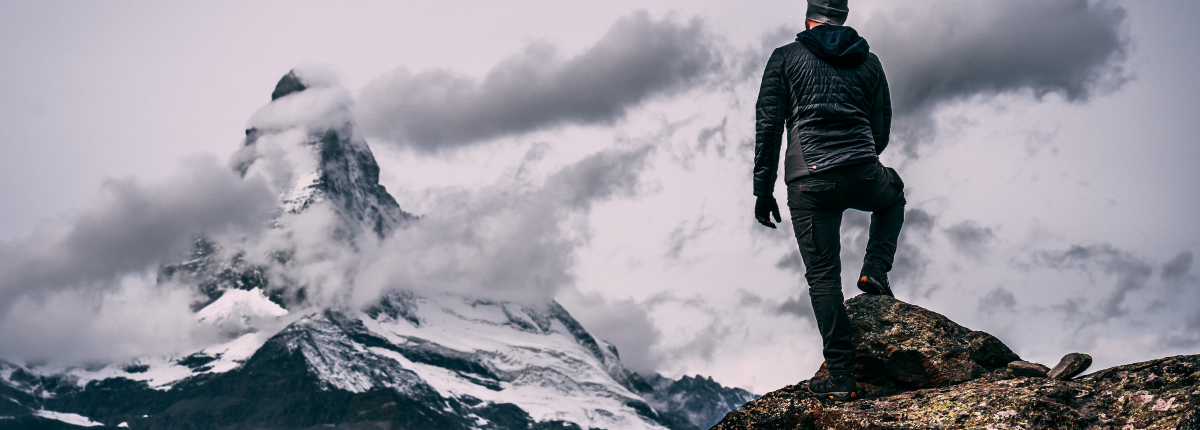 man on a mountain top from trail hiking