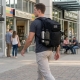 man walking with military tactical backpack loaded with everyday gear in a city