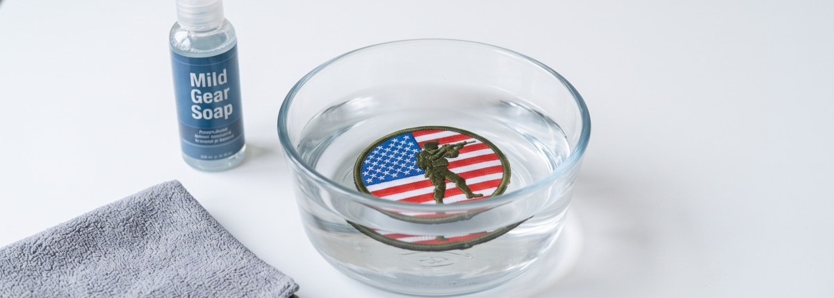 patch being soaked in a small basin of water with a bottle of liquid soap on a white table