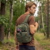 young man carrying a range shoulder bag in army green with forest background