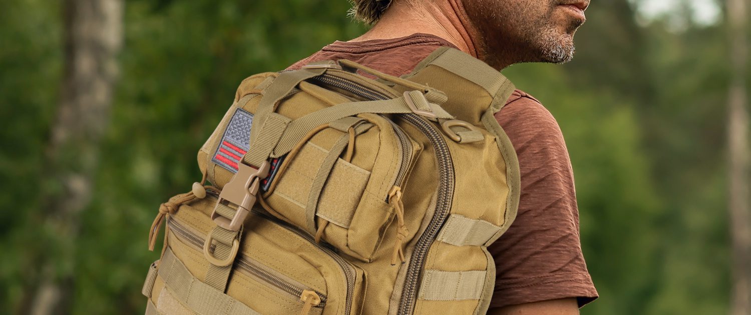 A rugged tactical sling bag on a rocky trail with accessories attached to its MOLLE webbing