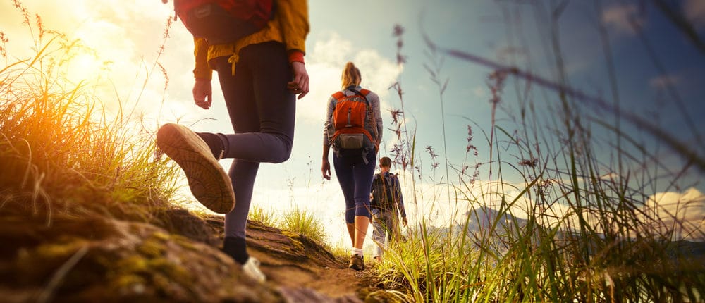 group of people hiking on grass hill top