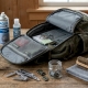 A sturdy backpack lying open on a wooden table with repair tools, cleaning brush, and waterproof spray nearby