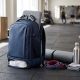 A stylish, water‑resistant gym backpack with mesh side vents, shoe compartment, and padded tech sleeve placed on a gym floor beside workout gear