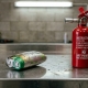 Close‑up of a swollen lithium battery next to a fire extinguisher, illustrating safety precautions
