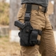 A tactical drop leg holster mounted on a thigh with a pistol visible, showing straps and modular pouches attached
