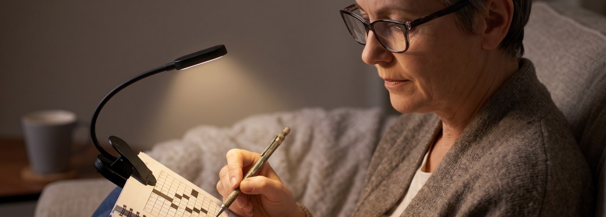 woman benefiting using a clip‑on light while doing a crossword puzzle