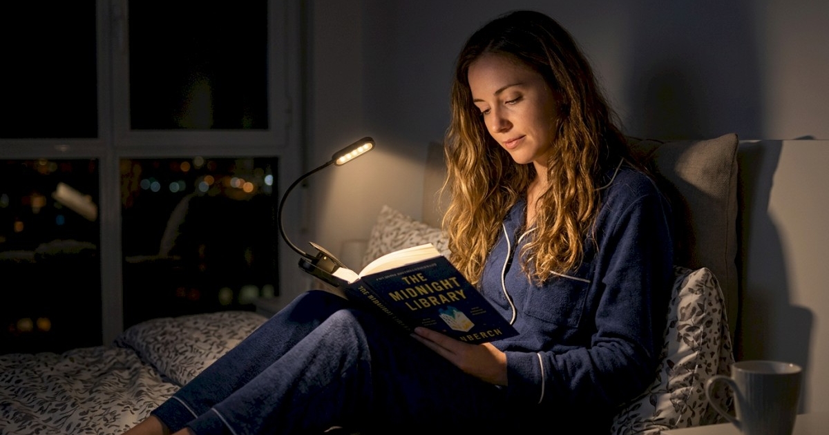 woman reading a book in bed at night with a clip-on rechargeable book light attached