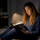 woman reading a book in bed at night with a clip-on rechargeable book light attached