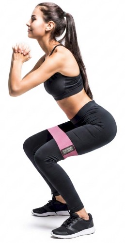 woman using butt exercise bands while doing squats on white background