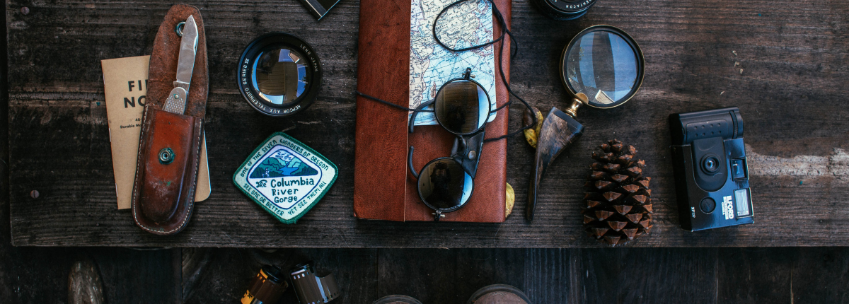 wooden table with a map, camera, flashlight, and knife